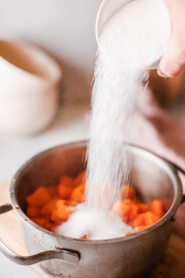 pouring sugar into softened and mashed cooked pumpkin
