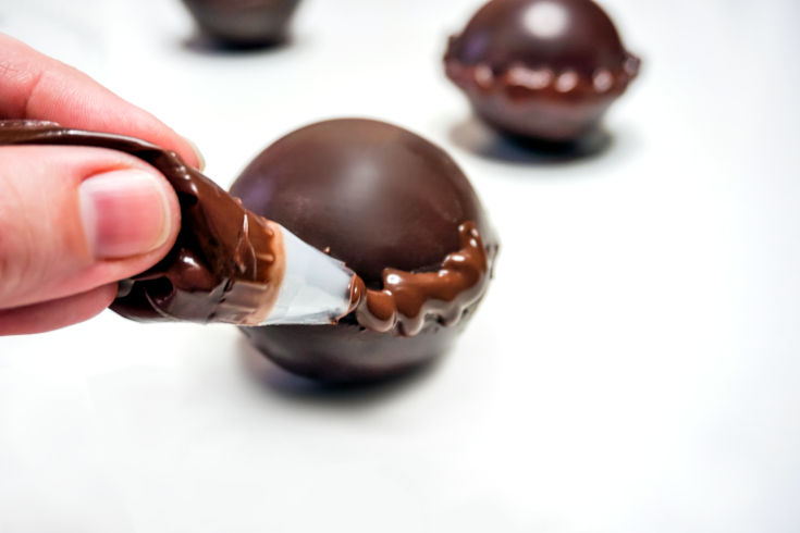 adding icing around diy hot chocolate bombs with corgi marshmallows