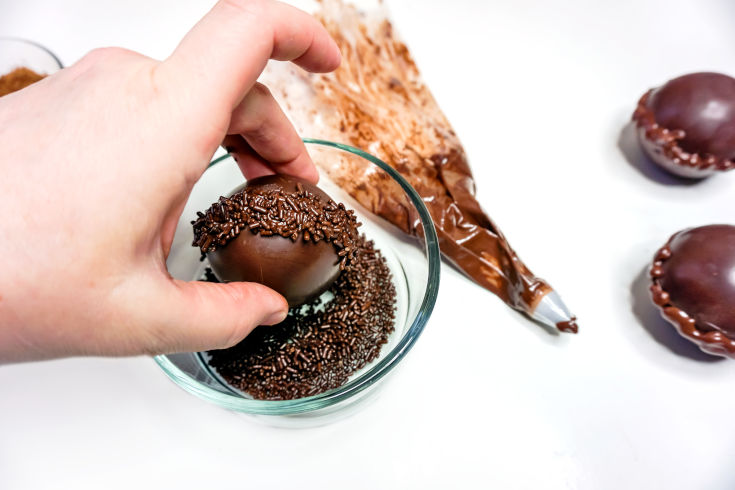 dip diy hot cocoa bombs in chocolate sprinkle decorations