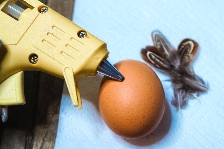 glue feathers onto hard boiled egg using a hot glue gun