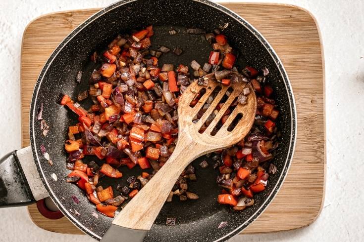 saute garlic onion red pepper to make zucchini vegetable fritters in frying pan