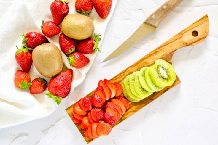 cut strawberries and kiwi into slices to make fruit popsicles
