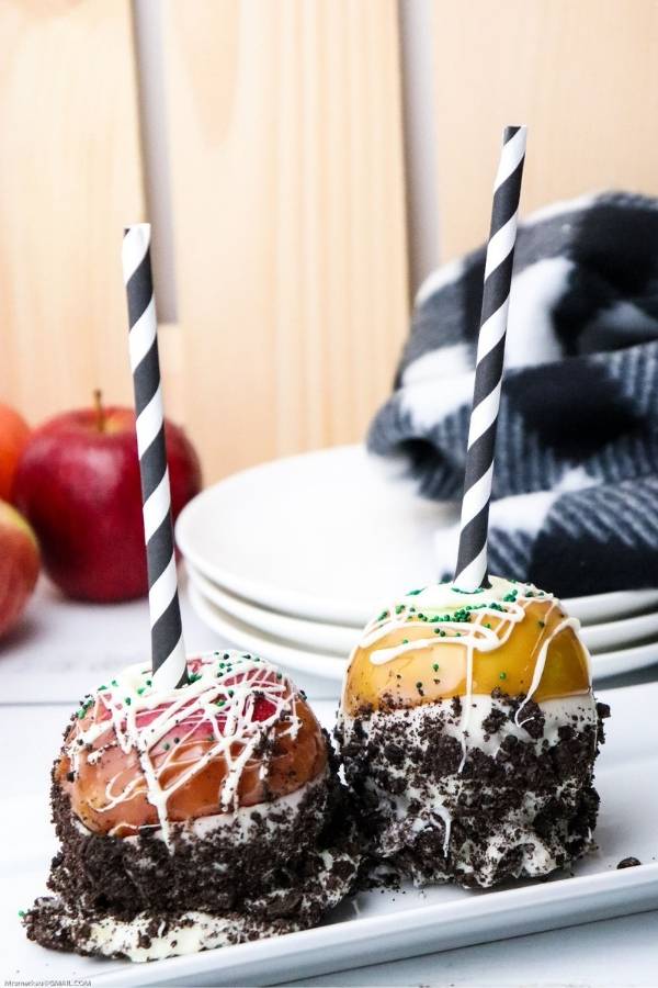 caramel dipped apples with decorative paper straws and crushed Oreo cookie toppings